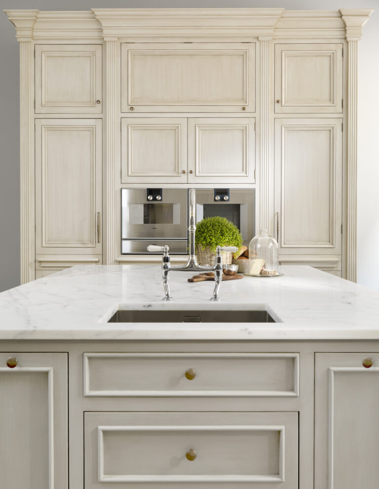 Hand-painted kitchen cabinetry with integrated ovens, a Carrara marble island and traditional bridge mixer tap