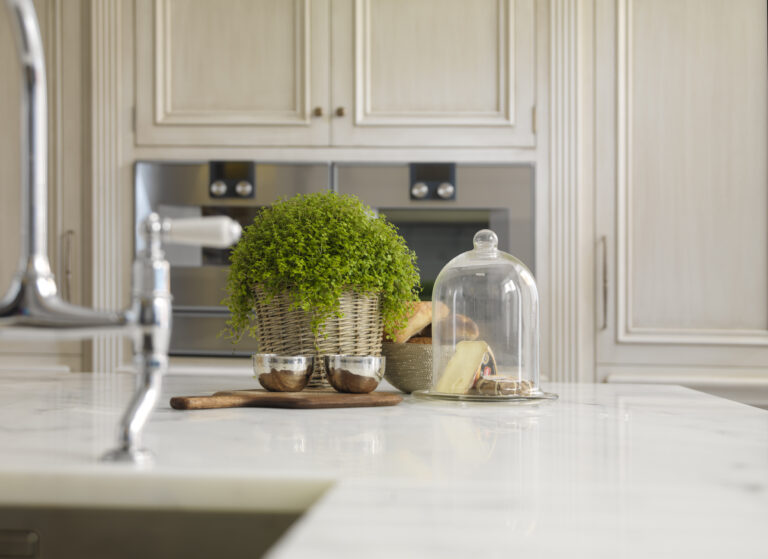 Carrara marble island with traditional tap, hand-painted cabinetry and integrated ovens in the background