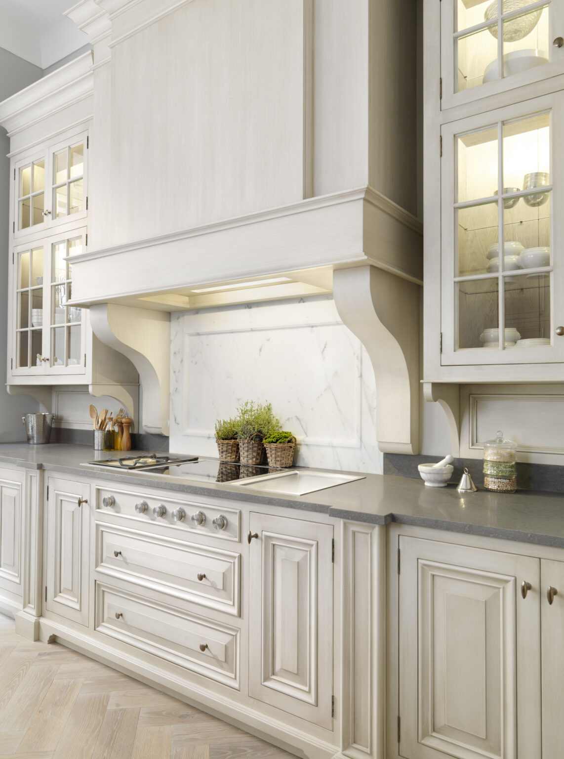 Hand-painted kitchen cabinetry with a Carrara marble splashback, panelled hood and illuminated glass display cabinets