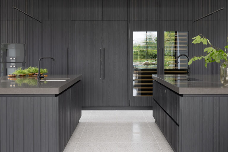 Kitchen with two fluted dark island units, integrated sinks, black taps and full-height panelled cabinetry
