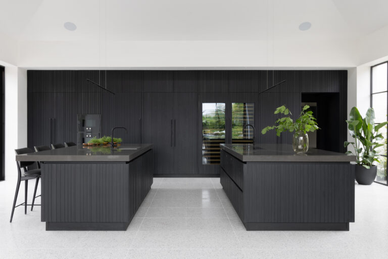Open-plan kitchen with twin fluted dark islands, matching grey worktops and floor-to-ceiling panelled cabinetry