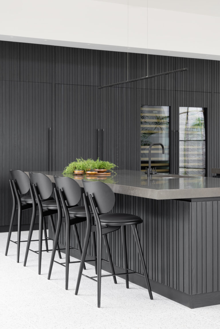 Fluted black kitchen island with stone worktop, black bar stools and integrated sink with tap