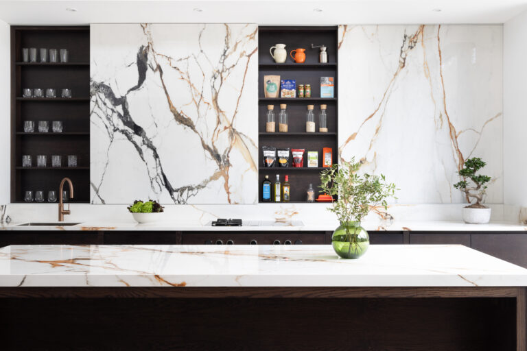 Open-plan kitchen with a striking wall of moving stone, dark cabinetry, open shelving and a stone island