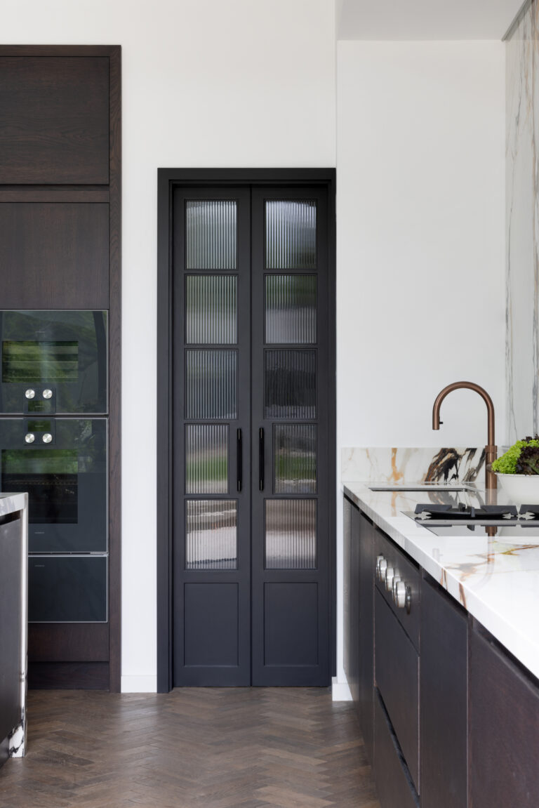 Dark kitchen with fluted glass pantry doors, built-in ovens, copper tap and XTONE Paonazzo Biondo stone splashback
