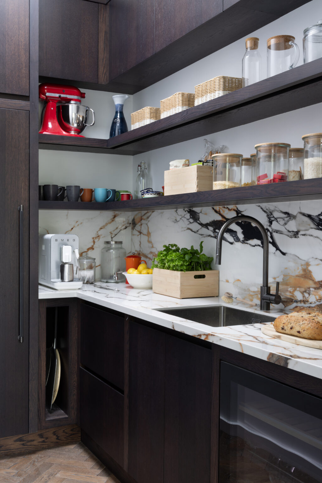 Walk-in pantry with open shelving, sink, and a wall of moving stone splashback above the counter