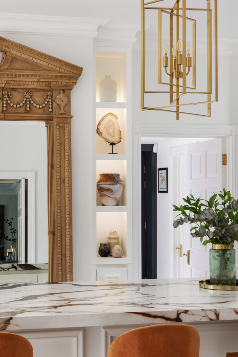 Kitchen featuring the antique mirror, XTONE island, brass pendant light and burnt-orange velvet stools beside a lit display niche