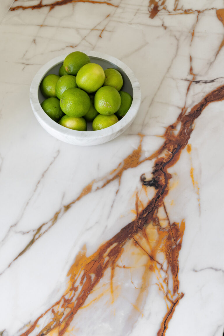 Bowl of limes resting on the XTONE island surface, showing its deep golden veining in close detail