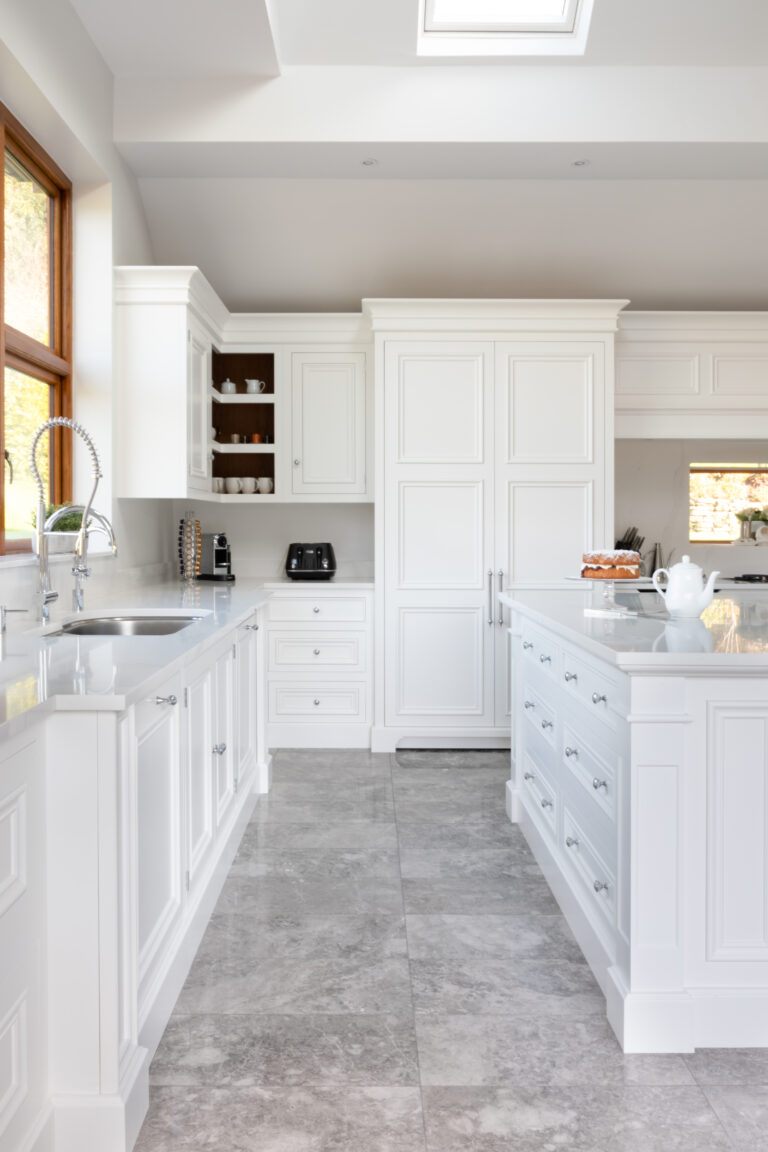 White painted kitchen with tall floor-to-ceiling cupboards, an island unit, Silestone worktops and a stainless steel sink