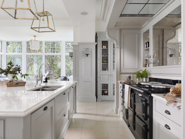 Bespoke kitchen with black Aga range, mirrored overmantel backsplash, island sink and brass pendant lighting