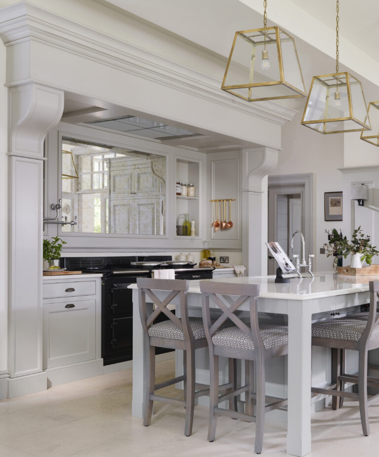 Bespoke kitchen with overmantel, black Aga, antique-style mirrored backsplash and brass pendant lights above the island