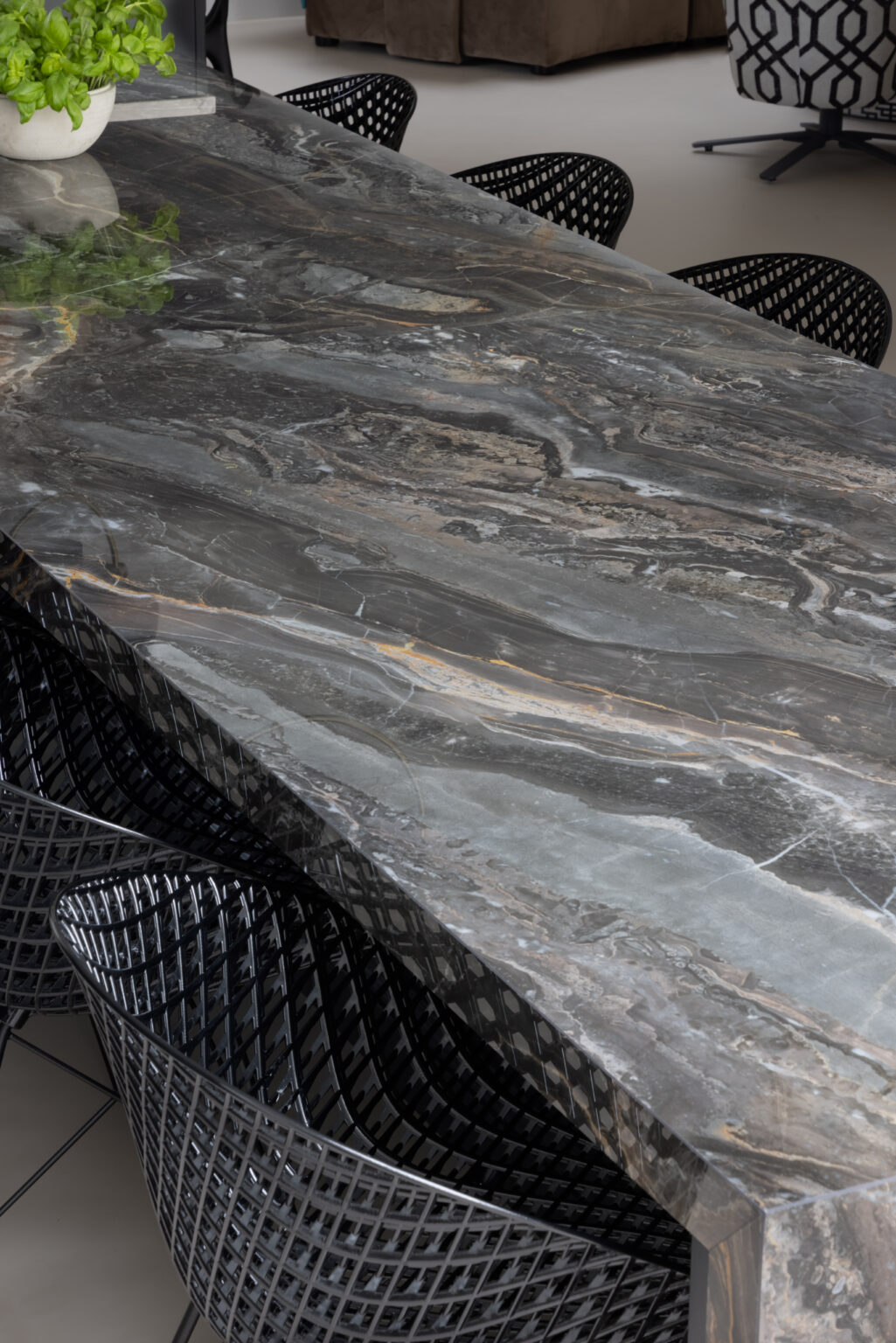 Close-up of the XTONE Orobico Dark stone island surface surrounded by black mesh dining chairs