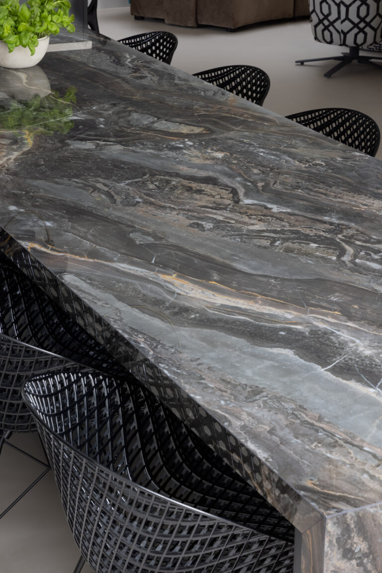 Close-up of the XTONE Orobico Dark stone island surface surrounded by black mesh dining chairs