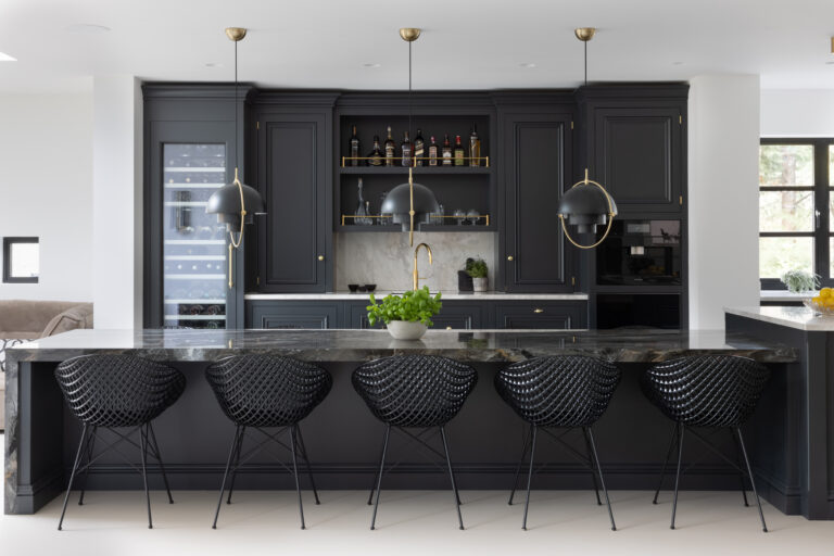 Dark kitchen island with XTONE Orobico Dark stone worktop, wire-back stools, brass pendant lights and built-in wine fridge