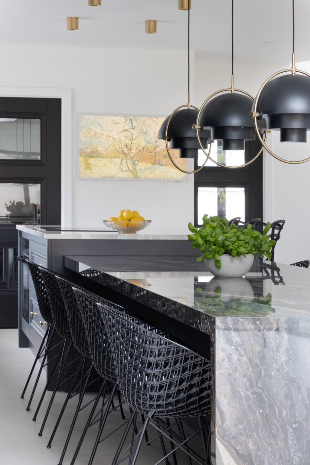 Kitchen island in XTONE Orobico Dark stone with black wire stools and three black and brass dome pendant lights above