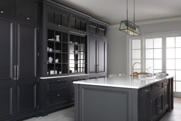 Black kitchen with a glazed display dresser, tall cabinetry and a central island topped with white stone