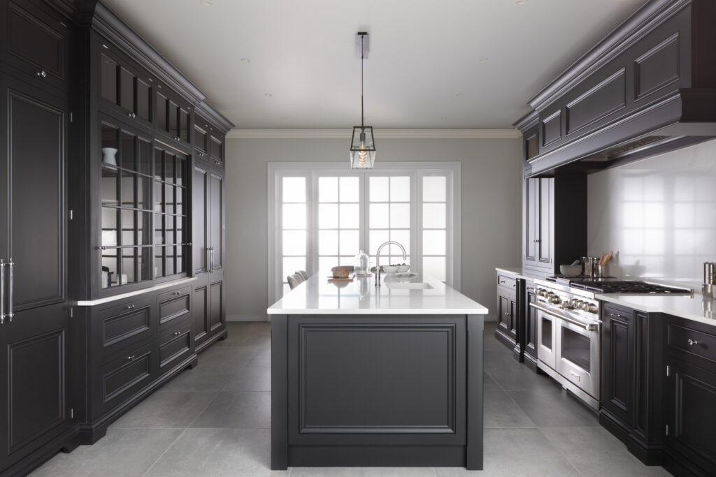 Dark cabinetry lines a kitchen with a central island, white stone worktops and a glazed dresser display