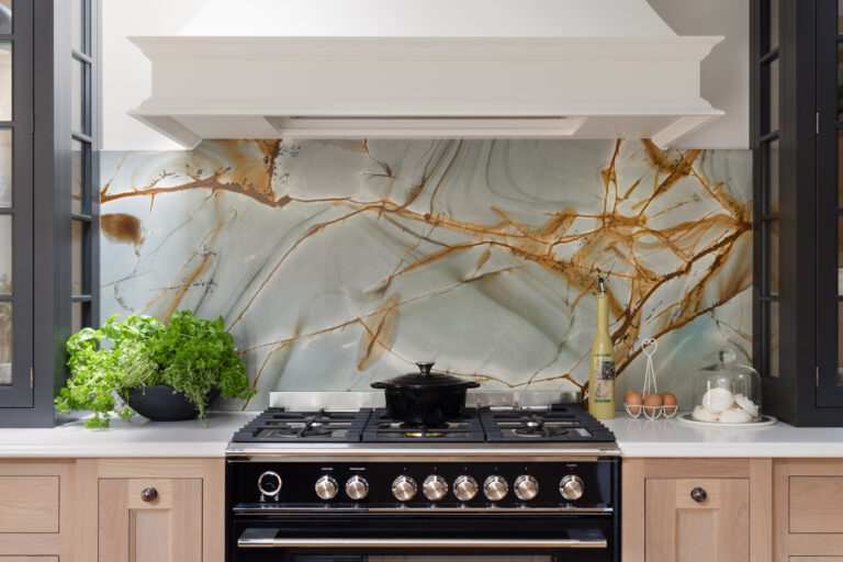 Range cooker beneath a backlit stone splashback with a white canopy hood and fresh herbs on the worktop