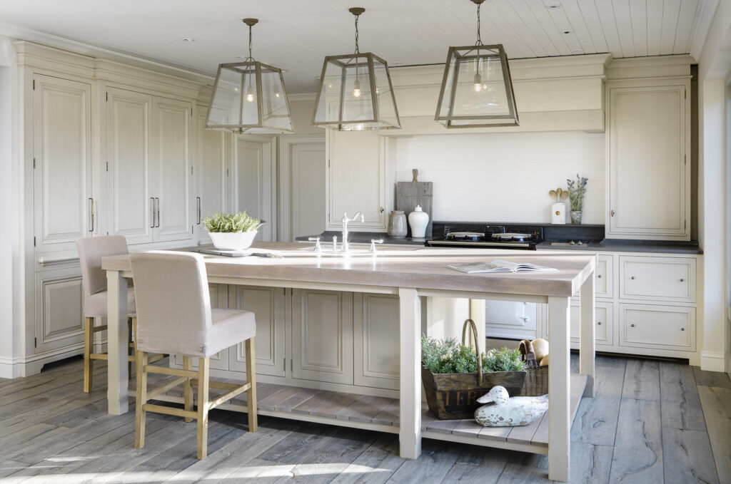 Bleached-oak kitchen island with open shelving beneath, paired with hand-painted cabinetry and glass pendant lights above