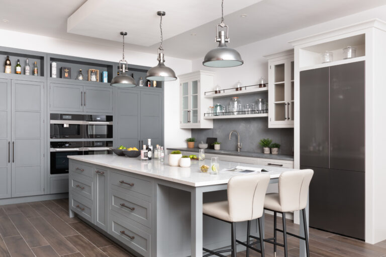 Kitchen island with bronze handles, stainless steel pendant lights, and built-in Miele appliances beside open shelving