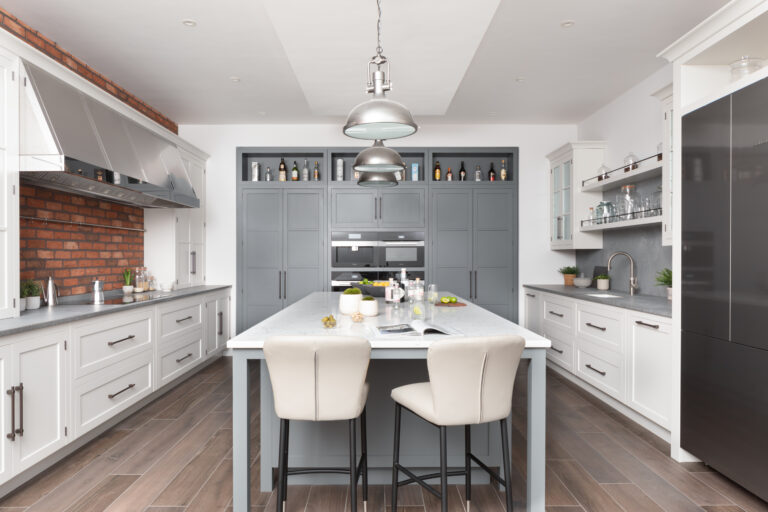 Kitchen island with bar stools, exposed brick splashback, stainless steel extractor and built-in Miele appliances