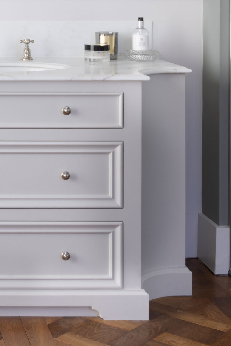 Bespoke bathroom vanity unit with panelled drawers, a stone-topped basin and traditional cross-head tap