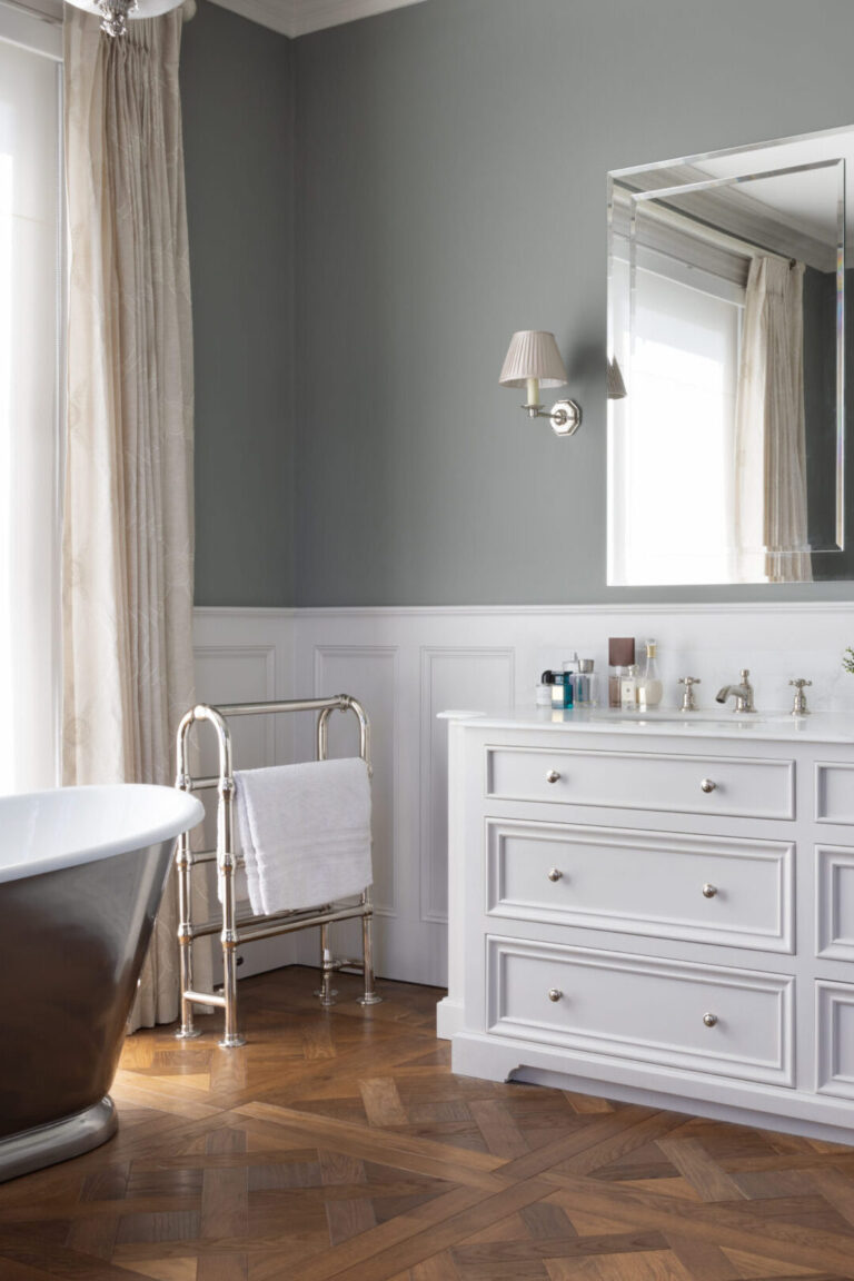 Bathroom with freestanding tub, heated towel rail and white double vanity dresser beneath a large mirror
