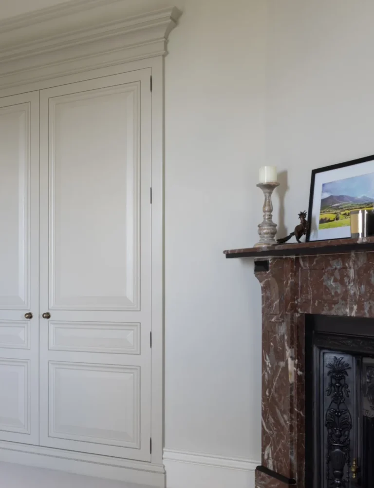 Bedroom alcove with panelled fitted wardrobe doors beside an original stone fireplace with cast iron insert