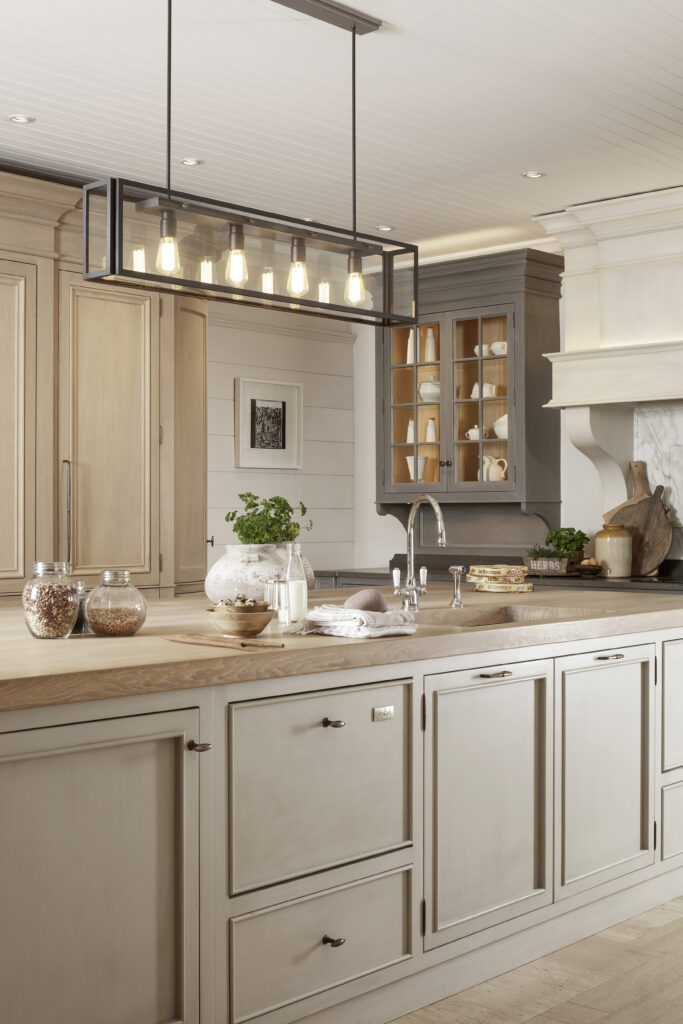 Kitchen island with timber worktop and integrated sink, glazed display cabinet and pendant light above