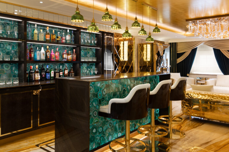 Green agate bar with backlit shelving, brass pendant lights and gold-trimmed bar stools in the lounge