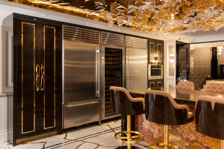 Kitchen with backlit onyx island, gold-trimmed cabinetry, steel appliances and a gold-leaf ceiling fitting overhead