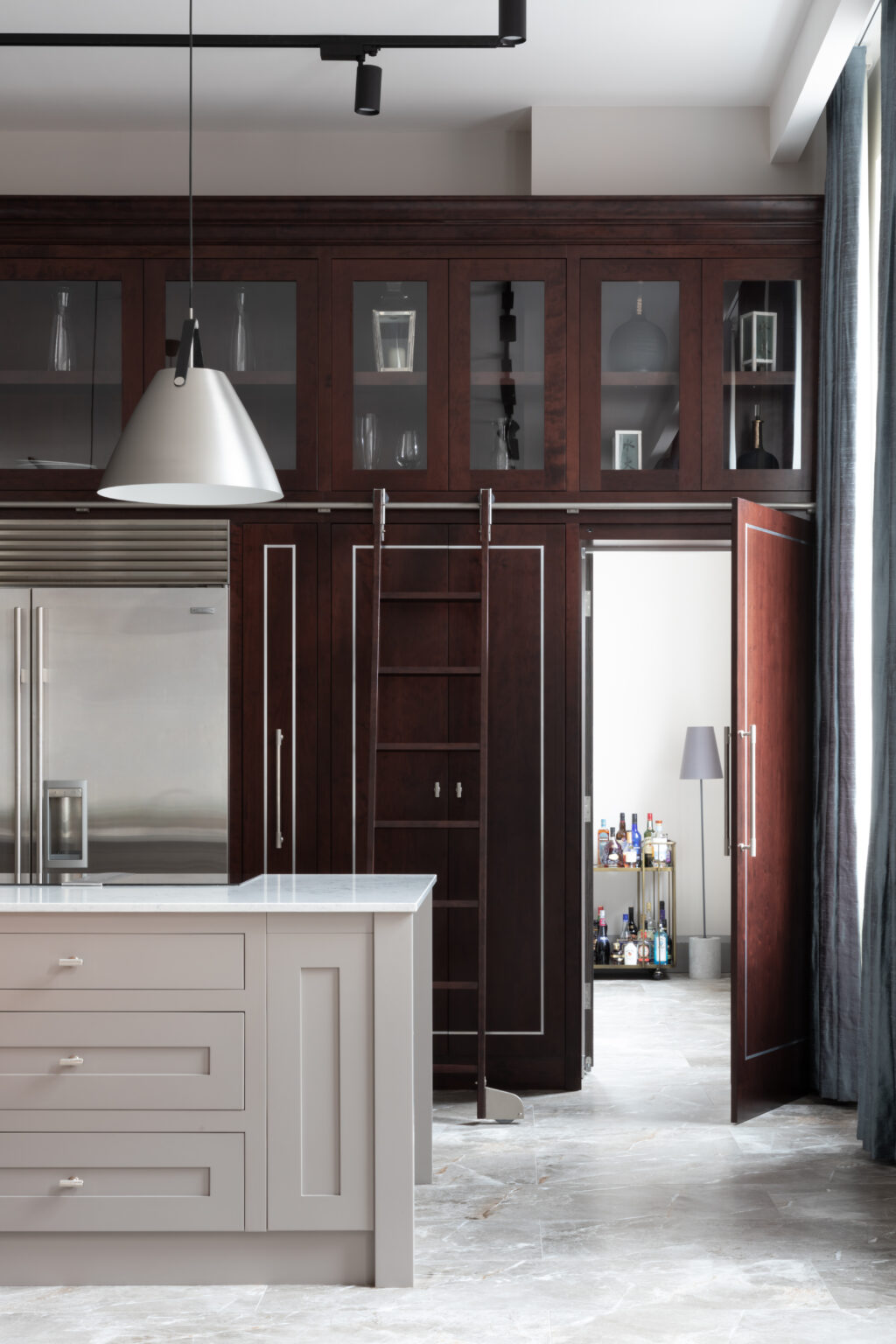 Kitchen with deep-stained cherry wood cabinetry, a sliding ladder, and a hidden door opening to a scullery bar