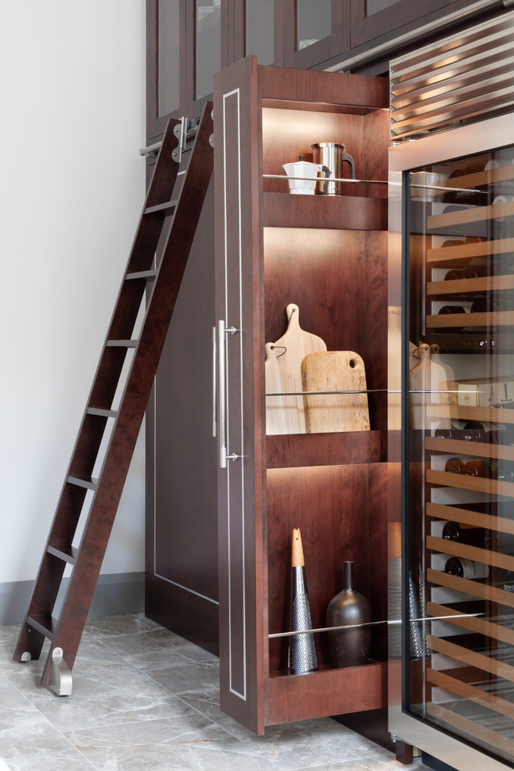 Deep-stained cherry wood cabinetry with a sliding ladder, pull-out shelving and a glass-fronted wine fridge