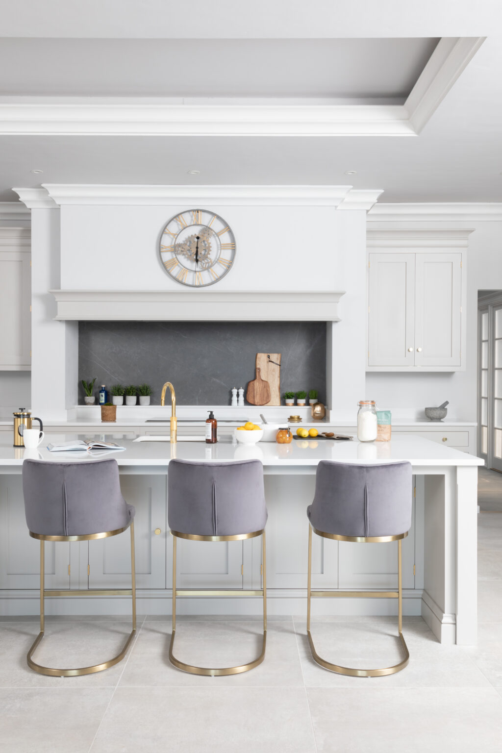 Central island with grey velvet bar stools and gold tap, set against Cornforth White cabinetry and a feature chimney breast