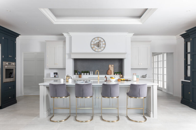 Symmetrical Cornforth White kitchen with a central island, grey velvet bar stools and a gold Quooker tap