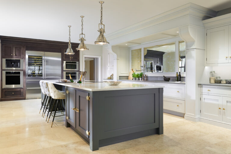 Large kitchen island in Down Pipe with Caesarstone worktop, brass latches, pendant lights and integrated champagne trough