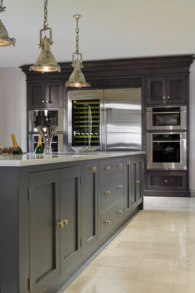 Kitchen island with Down Pipe cabinetry, brass handles and integrated wine fridge beside built-in ovens