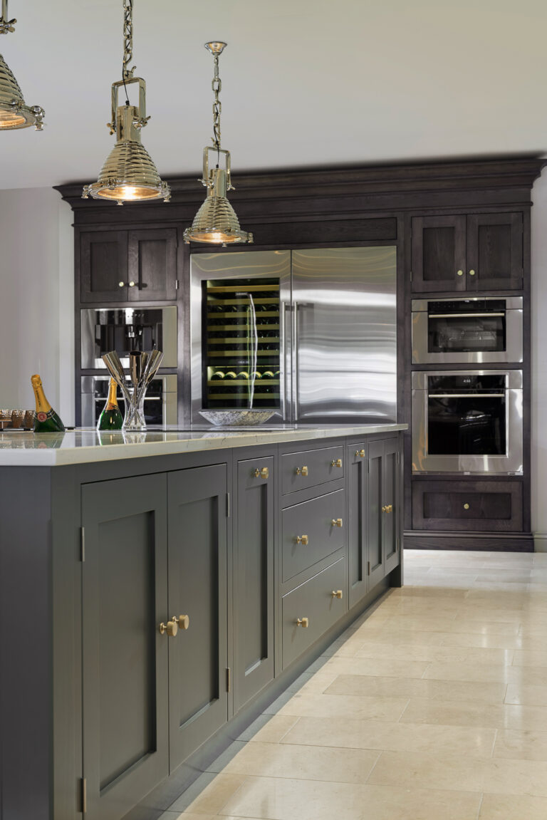 Kitchen island with Down Pipe cabinetry, brass handles and integrated wine fridge beside built-in ovens
