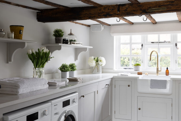 Laundry room with white cabinetry, exposed timber ceiling beams, integrated Miele appliances and a Belfast sink