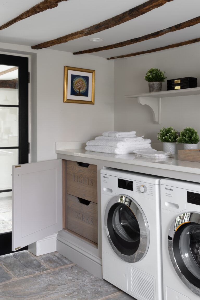 Laundry room with built-in Lights and Darks drawers, worktop above Miele washer and dryer, beneath original beams