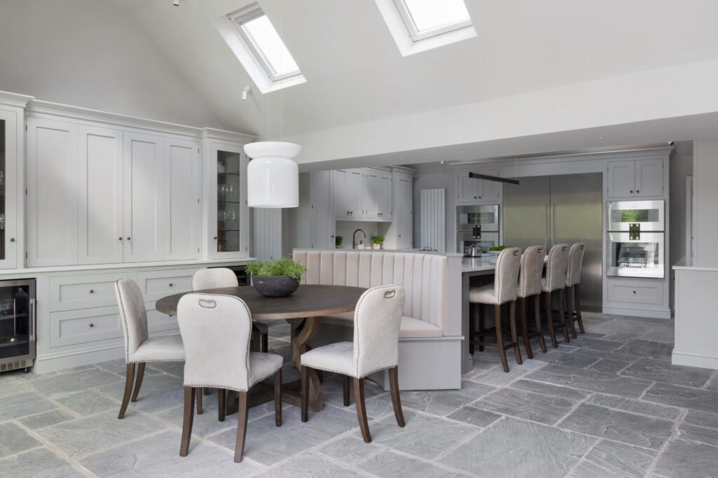 Vaulted kitchen with built-in banquette seating against the island, round dining table and bar stools on flagstone flooring
