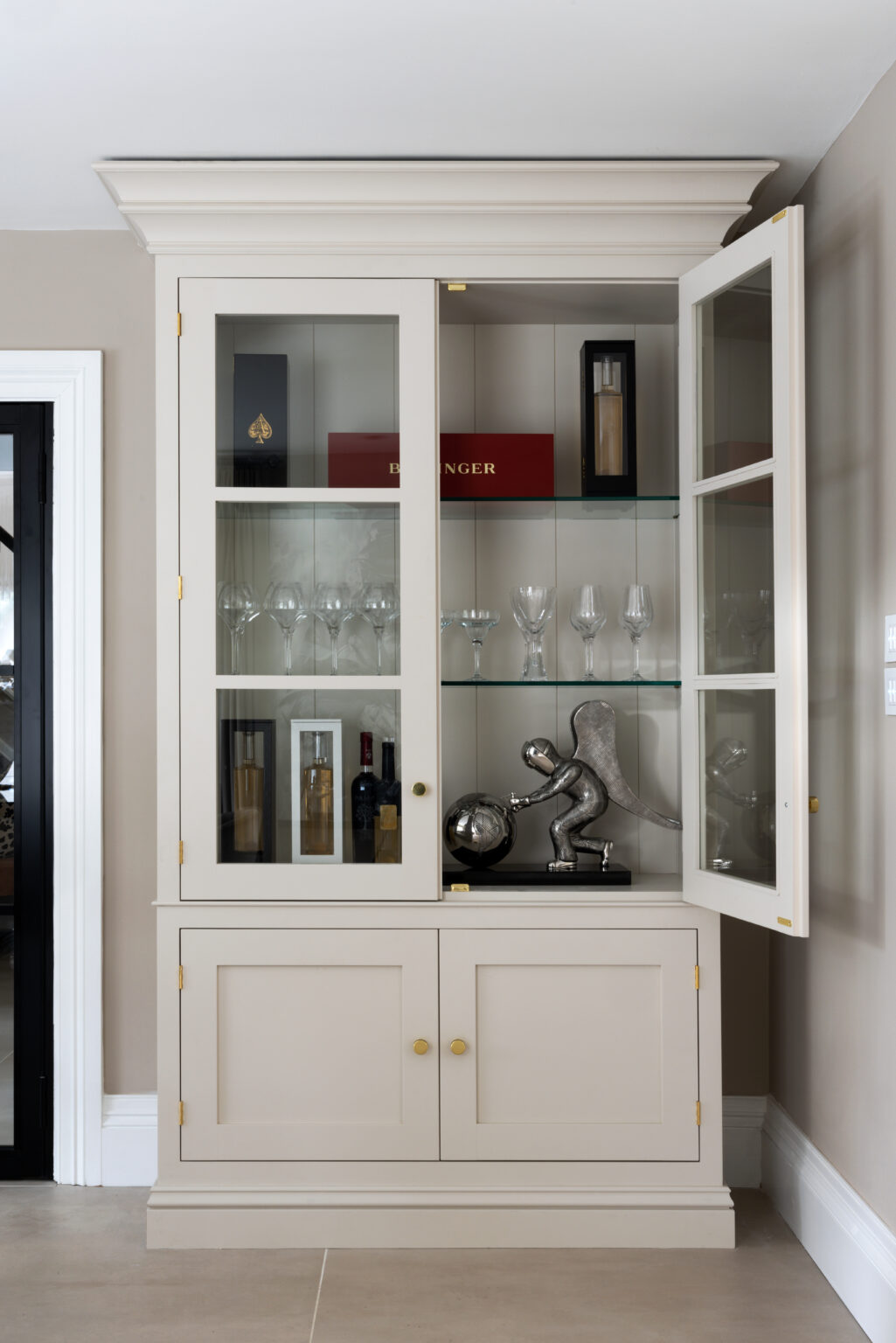 Classic glazed dresser with brass handles, glass shelves displaying wine glasses, bottles and an ornament