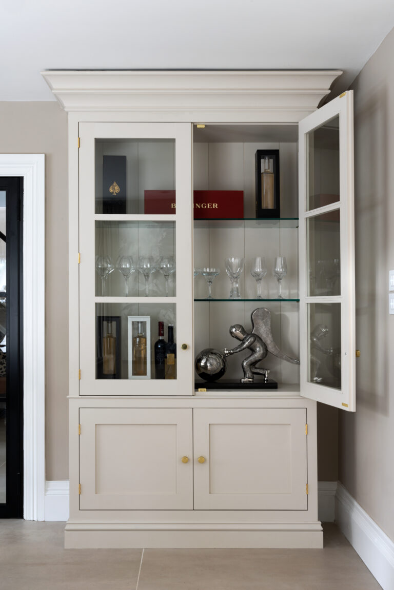 Classic glazed dresser with brass handles, glass shelves displaying wine glasses, bottles and an ornament