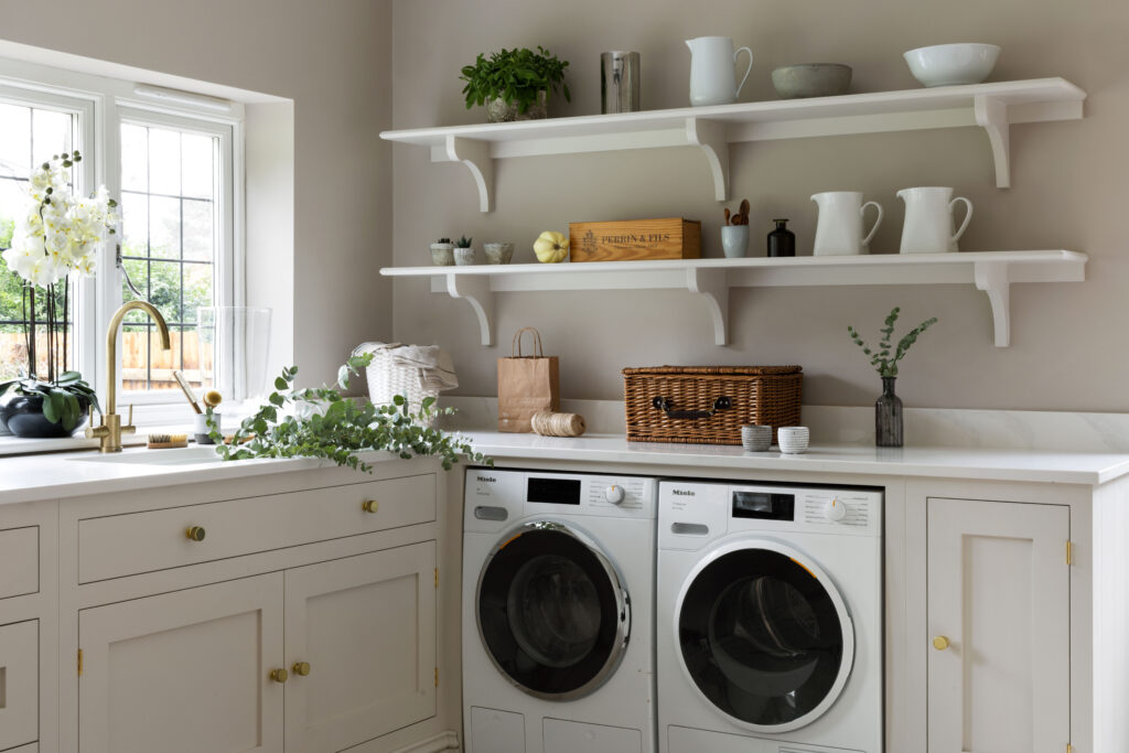 Creamy white Shaker cabinetry with open shelving, corbel brackets and an antique brass tap above integrated Miele appliances