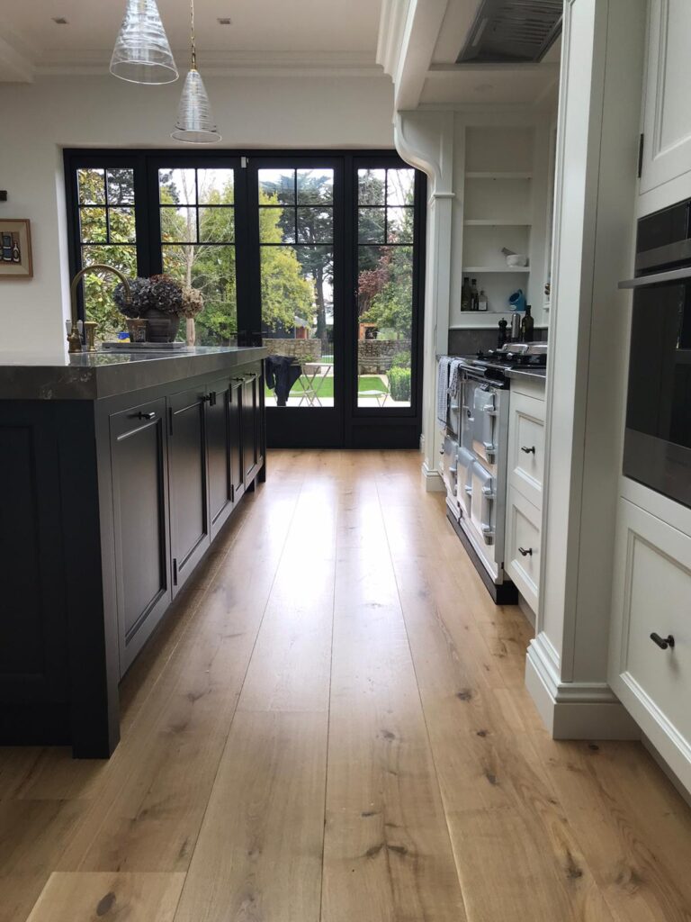 Kitchen with a dark island unit, wooden flooring, a traditional range cooker and tall glazed doors opening to the garden