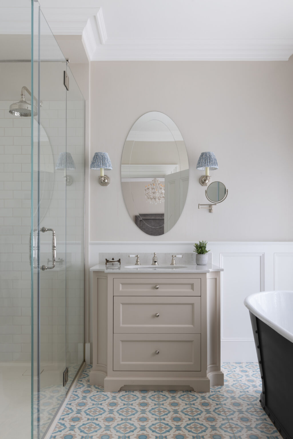 Master bathroom with a bespoke vanity unit, oval mirror, walk-in shower and freestanding roll-top bath on patterned tiled flooring