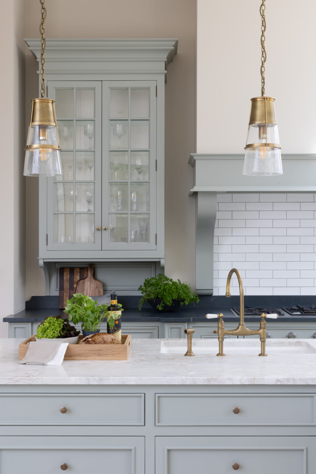 Sage Green kitchen with glazed dresser, brass pendant lights and a bridge tap over the island sink