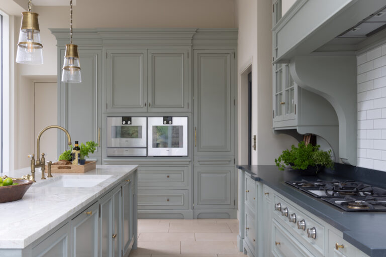 Sage Green bespoke kitchen with built-in double ovens, stone island, brass taps and a gas hob