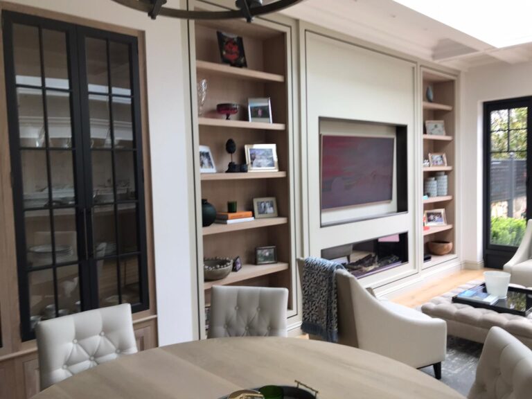 Open-plan living area with bespoke fitted shelving, glazed display cabinet, fireplace and built-in television unit