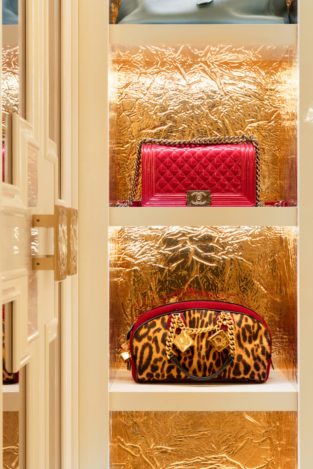 Dressing room shelving with gold-leaf backed alcoves displaying designer handbags, finished with gold hardware fittings