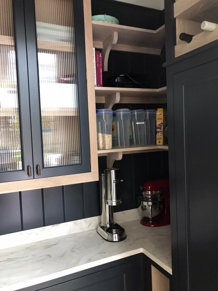 Pantry corner with open shelving, glazed cupboard doors and a worktop holding storage jars and a mixer
